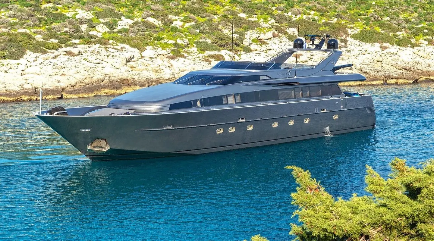 Motor yacht Summer Fun anchored in blue sea with rocky shoreline nearby