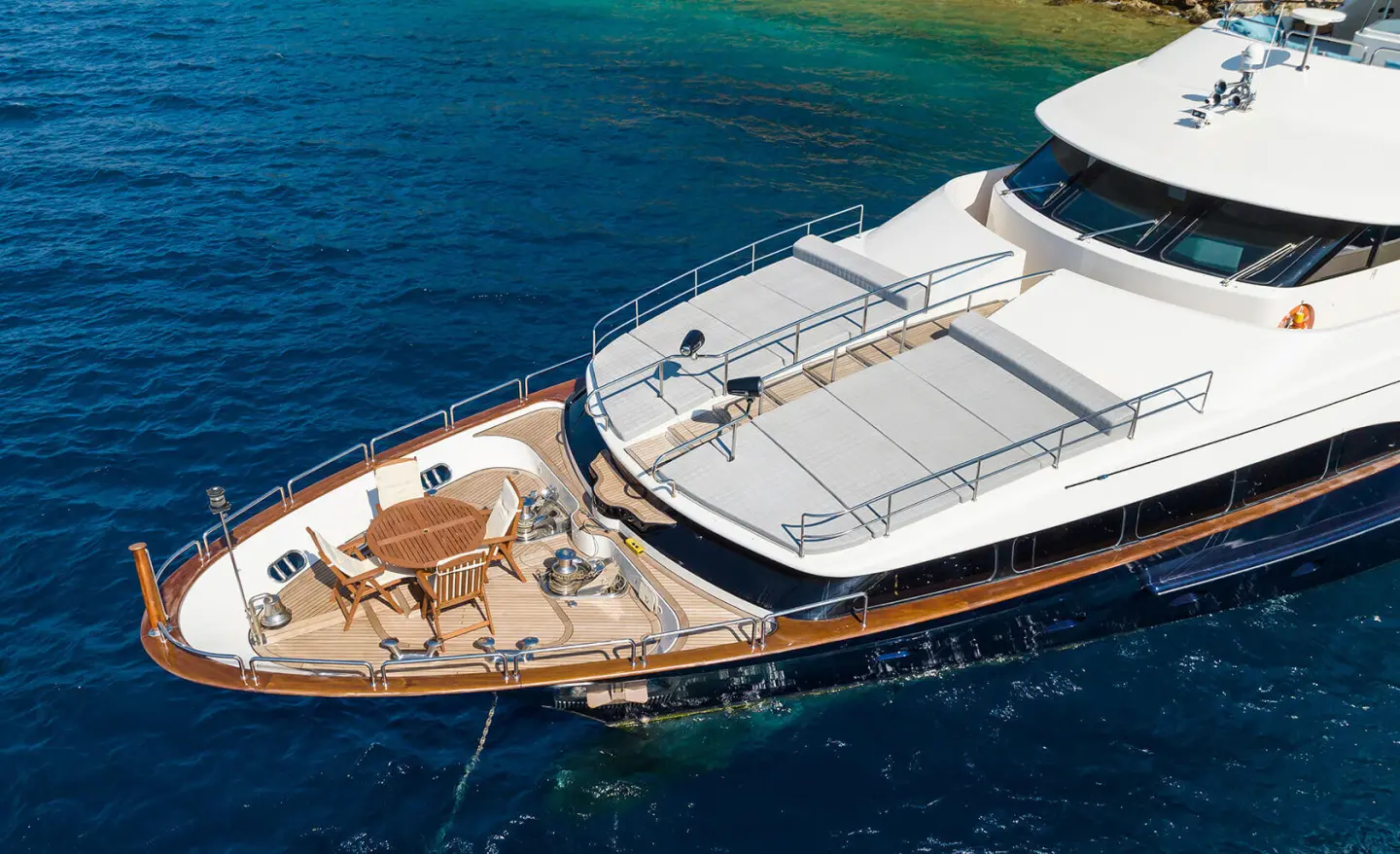 A luxury motor yacht Amadea at anchor with deck chairs on bow and clear blue water