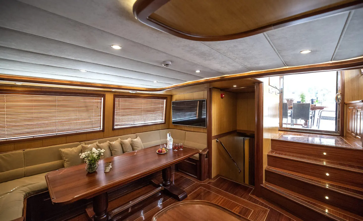 Kayhan 3 yacht interior with wooden panels, seating, and a dining area at sunset
