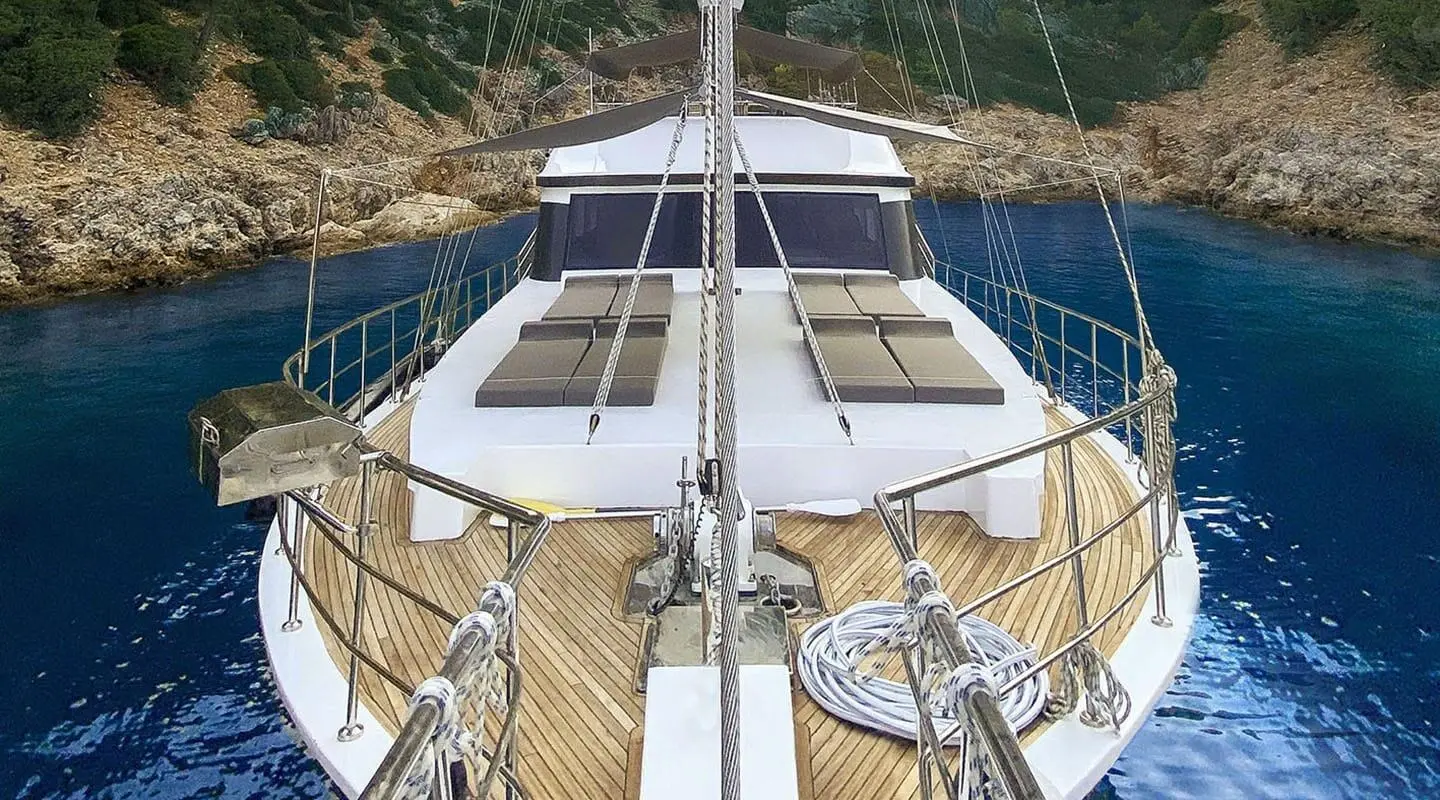 View from bow of Maske 5 yacht showing deck, railing, and anchor lines at sunset