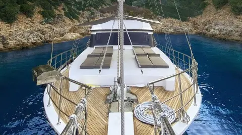 View from bow of Maske 5 yacht showing deck, railing, and anchor lines at sunset