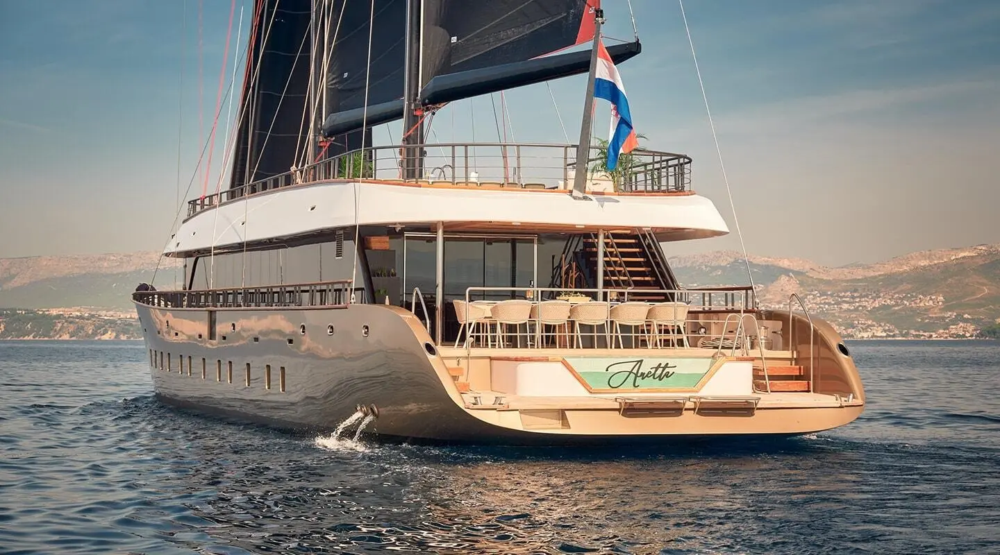 Aretha yacht seen from rear with open deck and dining chairs on a luxury motor yacht