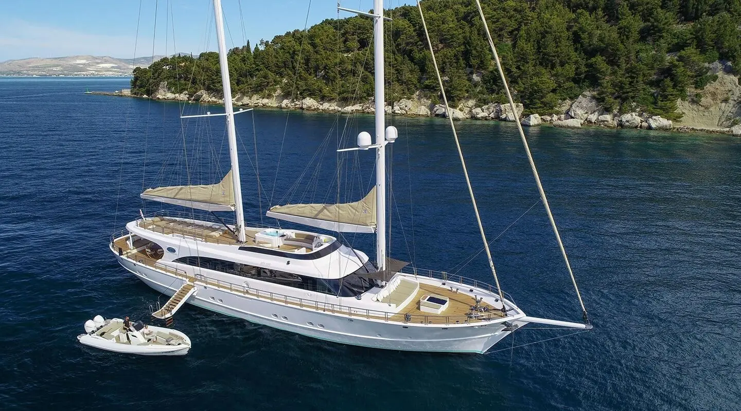 Acapella yacht anchored near shore, white hull, blue sail cover, calm water