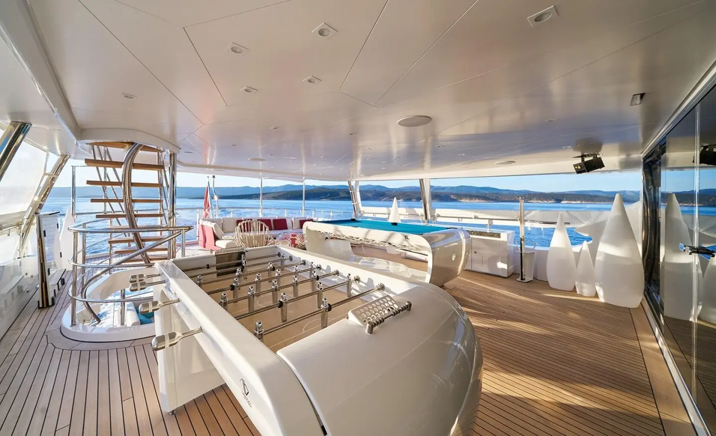 Deck seating area aboard Happy Me luxury yacht with white cushions and sun loungers