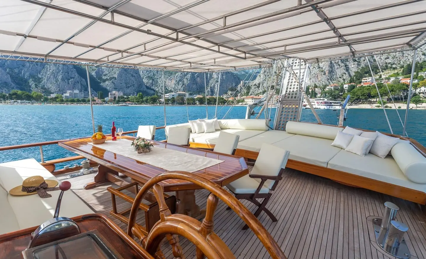 Andi Star gulet aft deck with wooden helm wheel and seating under shade
