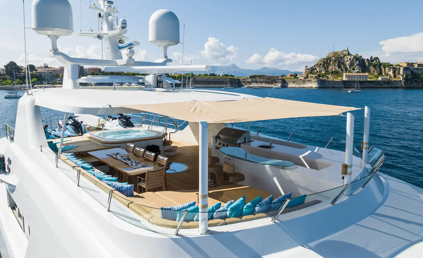 Sunlit exterior deck with lounging area, dining table, and built-in bar
