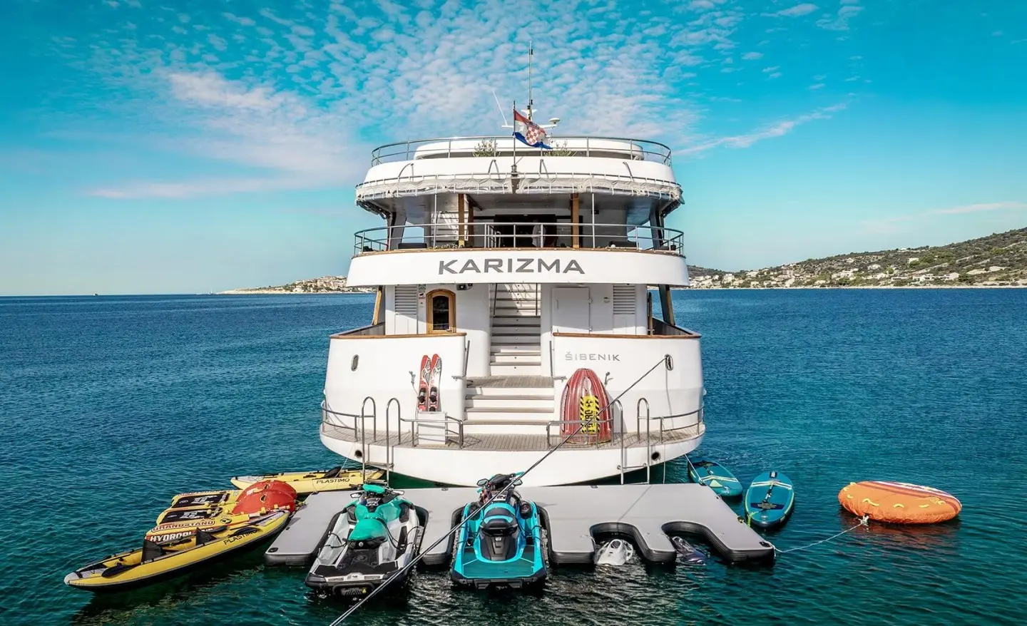 Karizma yacht anchored with blue sea, clear sky, and jet skis nearby