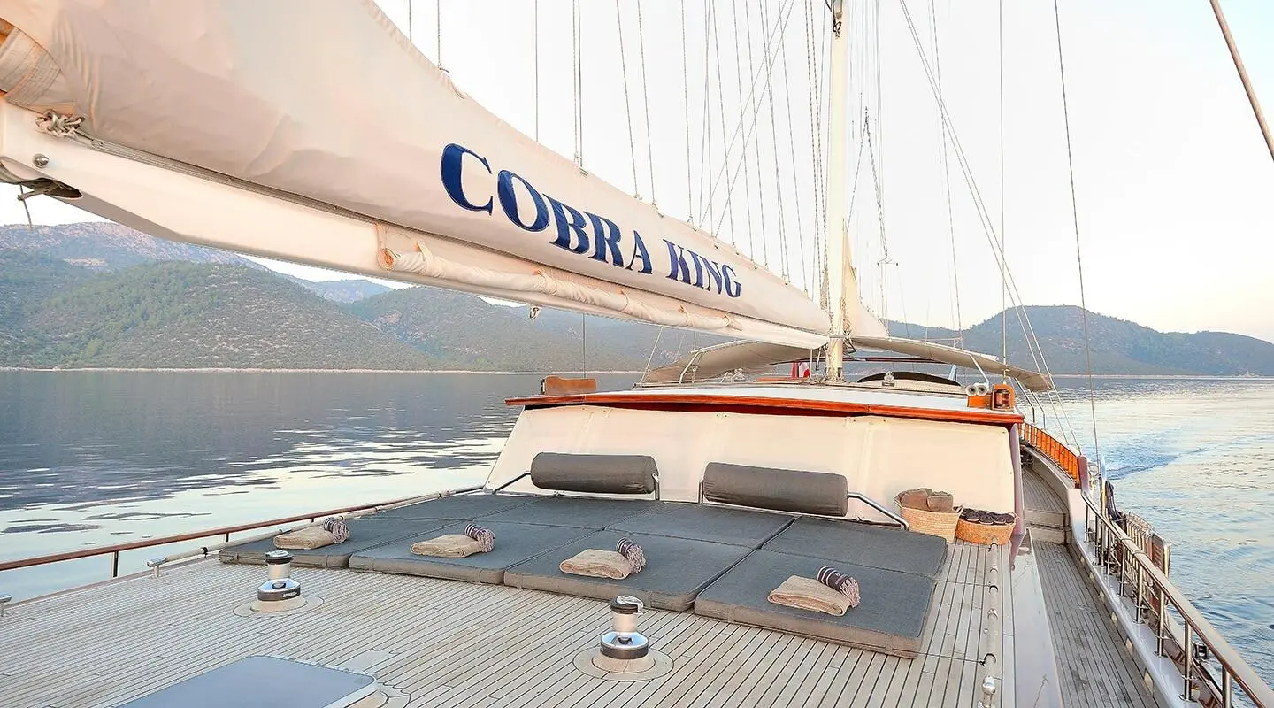 Cobra King yacht deck and sailboat rigging at sunset with calm water