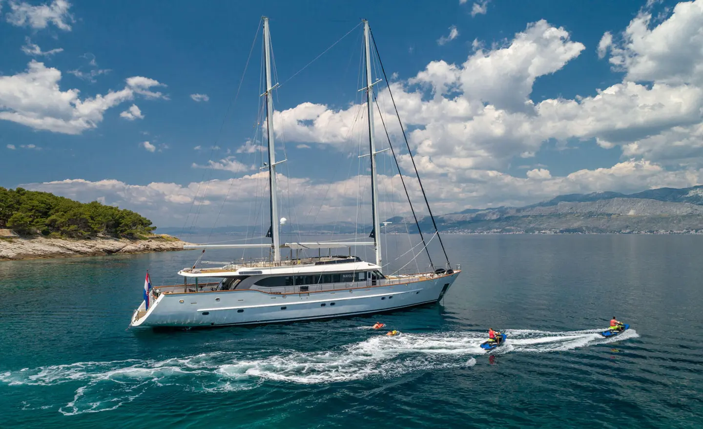 Navilux luxury yacht anchored on calm blue sea at sunset with sails up