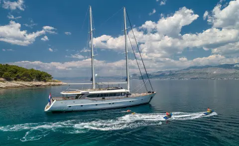 Navilux luxury yacht anchored on calm blue sea at sunset with sails up