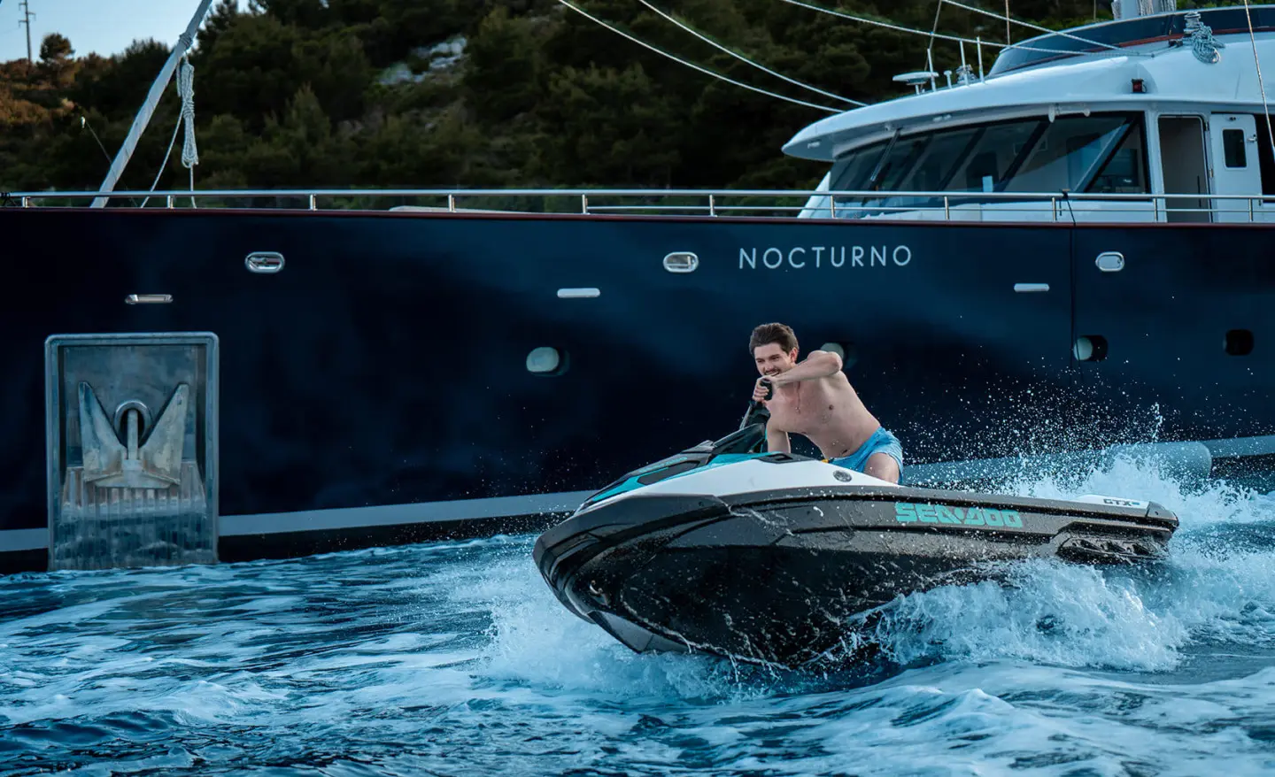 Nocturno luxury yacht on calm water with a person in a small motor boat nearby