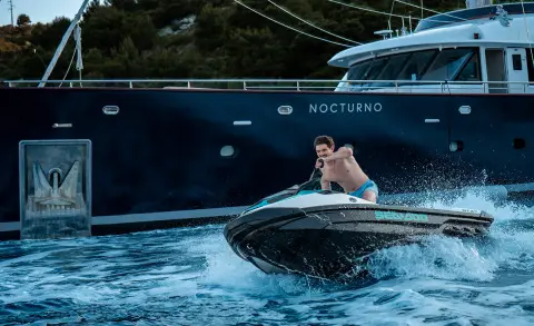Nocturno luxury yacht on calm water with a person in a small motor boat nearby