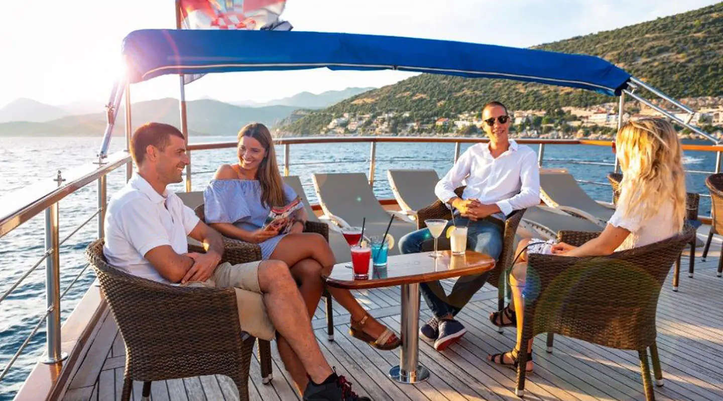 Five people on a luxury yacht Mendula deck enjoying drinks at sunset