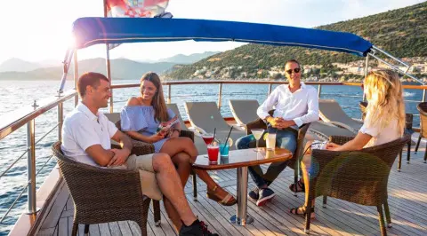Five people on a luxury yacht Mendula deck enjoying drinks at sunset