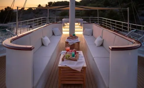 Bellezza motor yacht sun deck with seating, table, and snacks at dusk