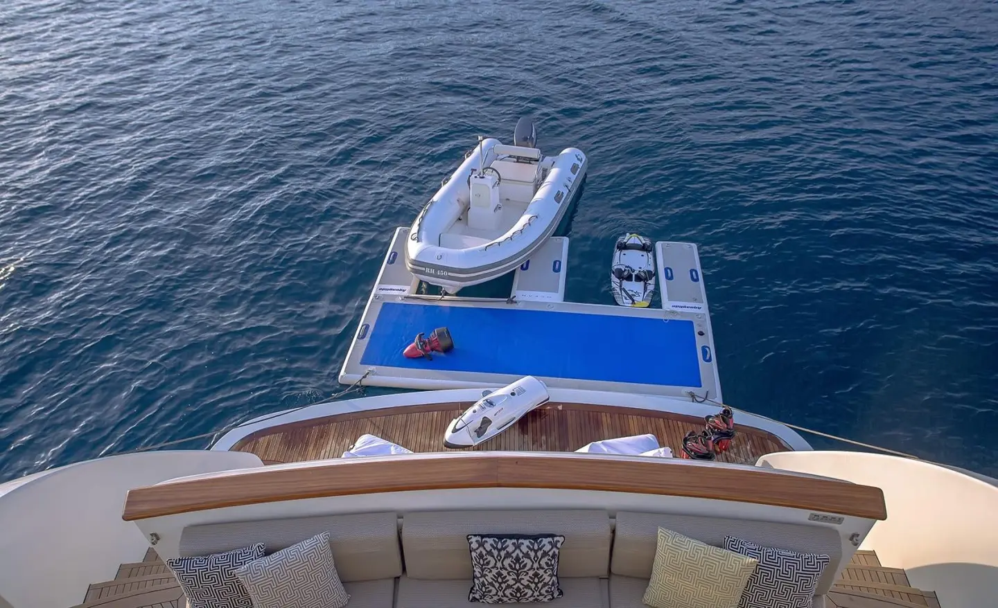 Aquila yacht deck view with blue water, upper deck seating, and a small tender