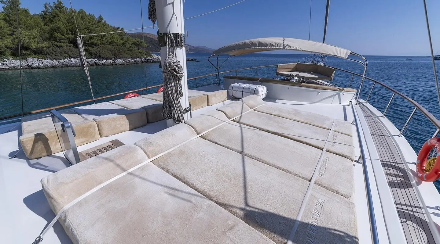 Sunny deck with large cushioned sunbeds on a luxury yacht with seating and shade canopy