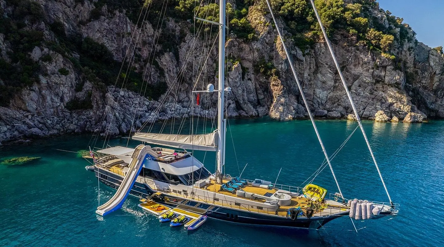 Gulet Good Life anchored with colorful kayaks beside the yacht in a calm cove