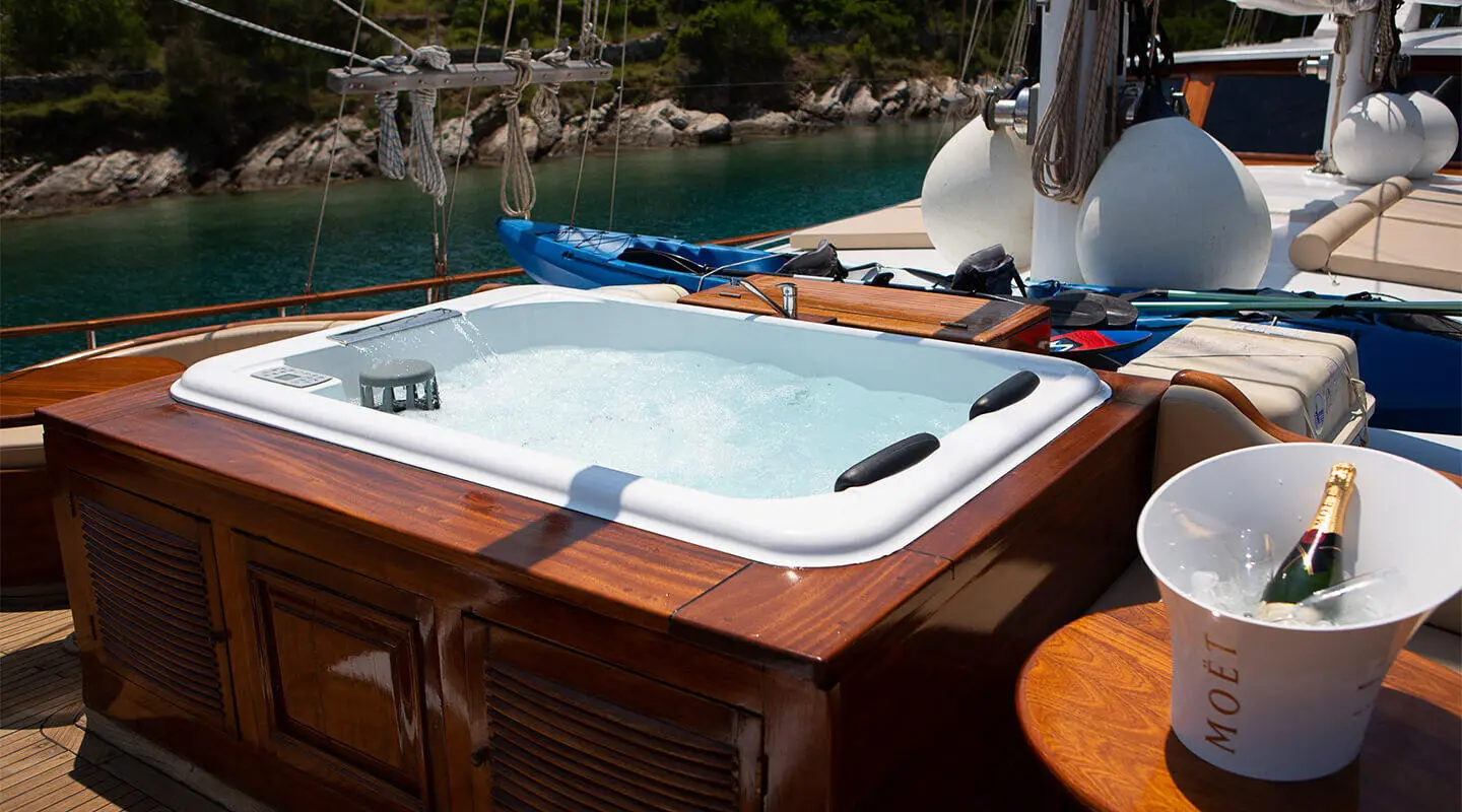 Dolce Vita yacht deck with a white jacuzzi, wooden panels, and blue water