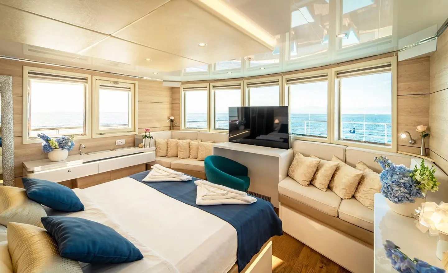 Luxurious yacht cabin with cream leather seating, beds, and large windows