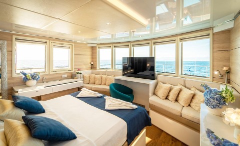 Riva yacht VIP cabin with large windows, sea view, decorative flowers and a cozy seating area