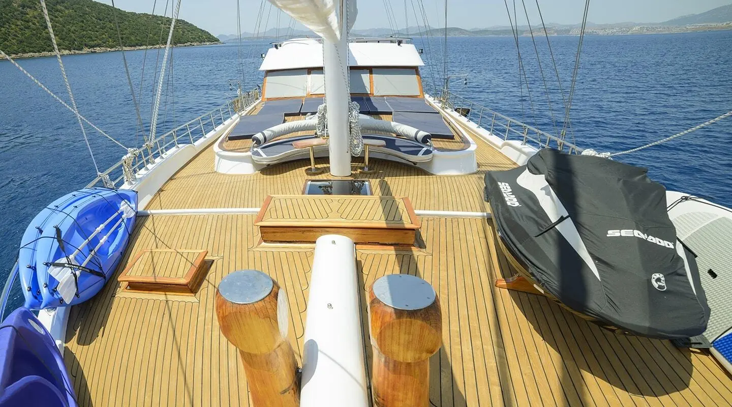 Yacht Bella Mare deck with sun loungers, wooden deck, and open sea view at sunset