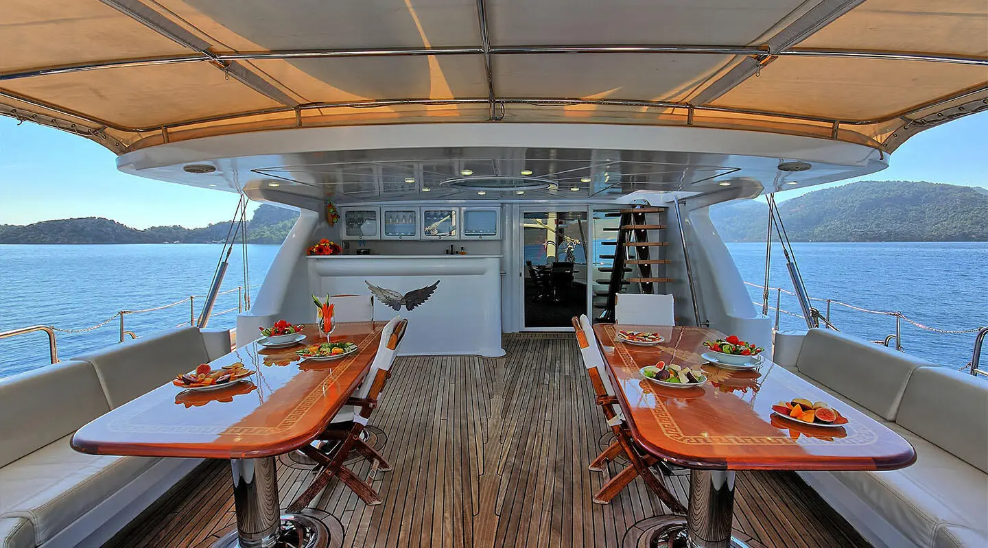Angelo II yacht crewed dining area with wooden tables on deck at sunset