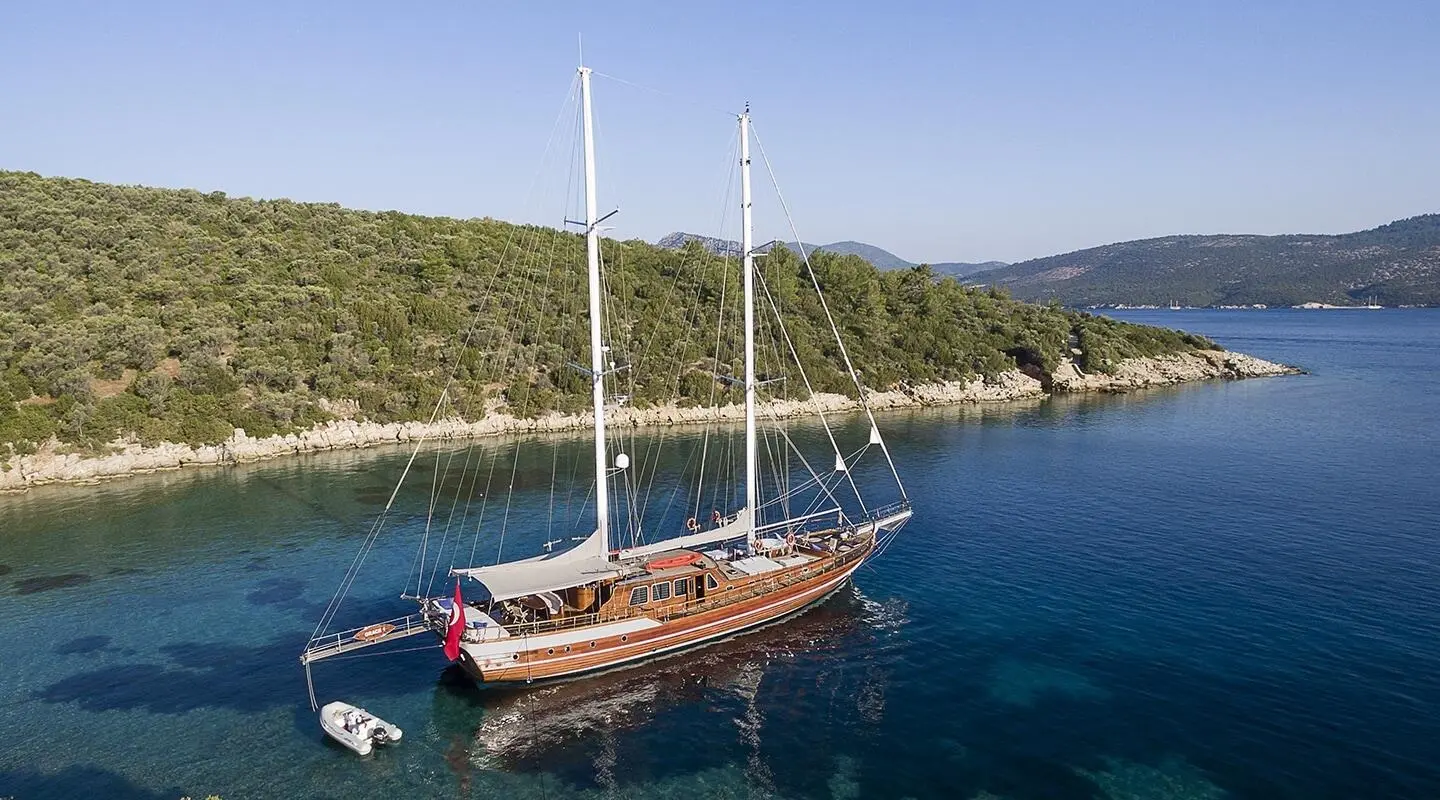 Grace 1 yacht anchored in calm blue harbor with rocky coastline