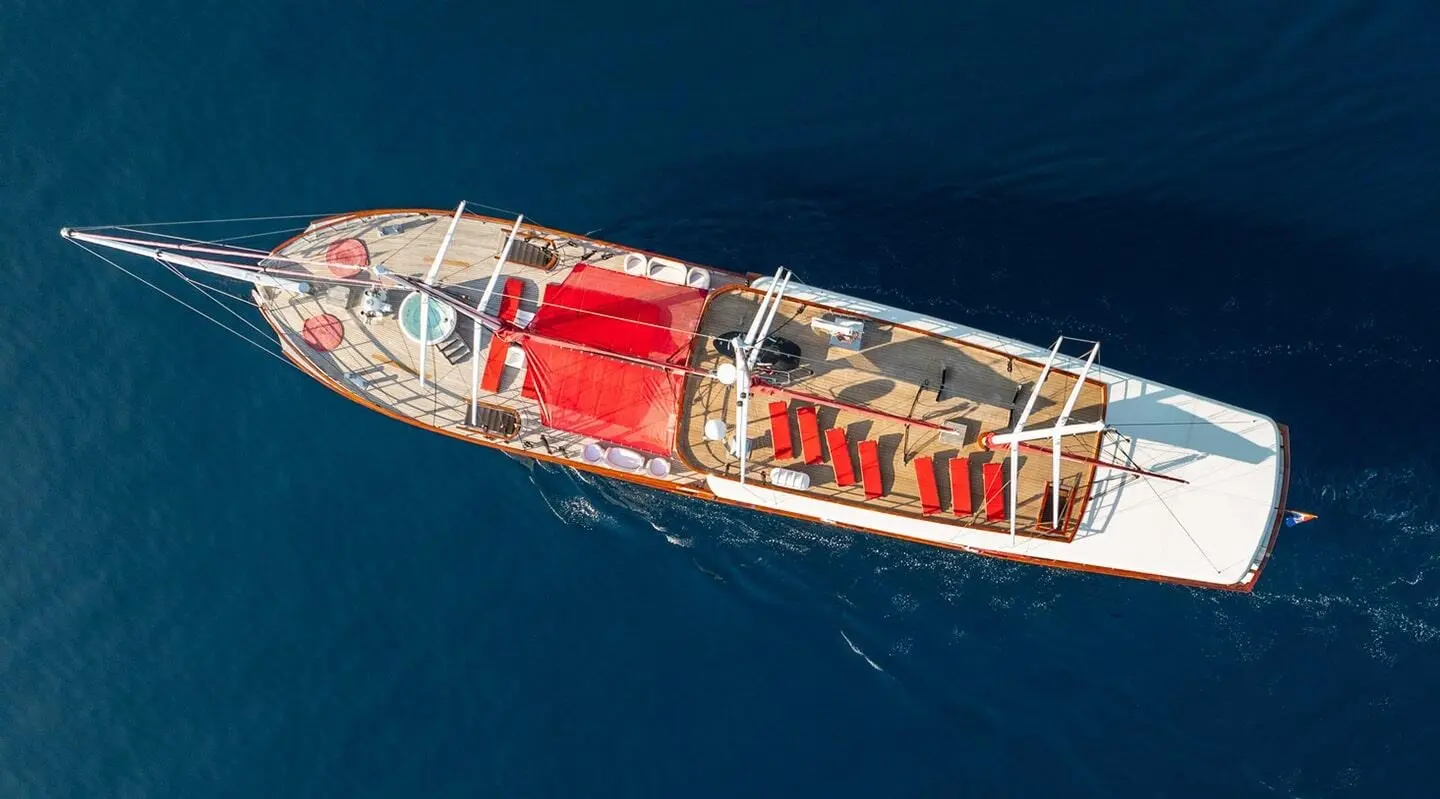 Aerial view of Barbara yacht with red deck seating and sun loungers on blue sea