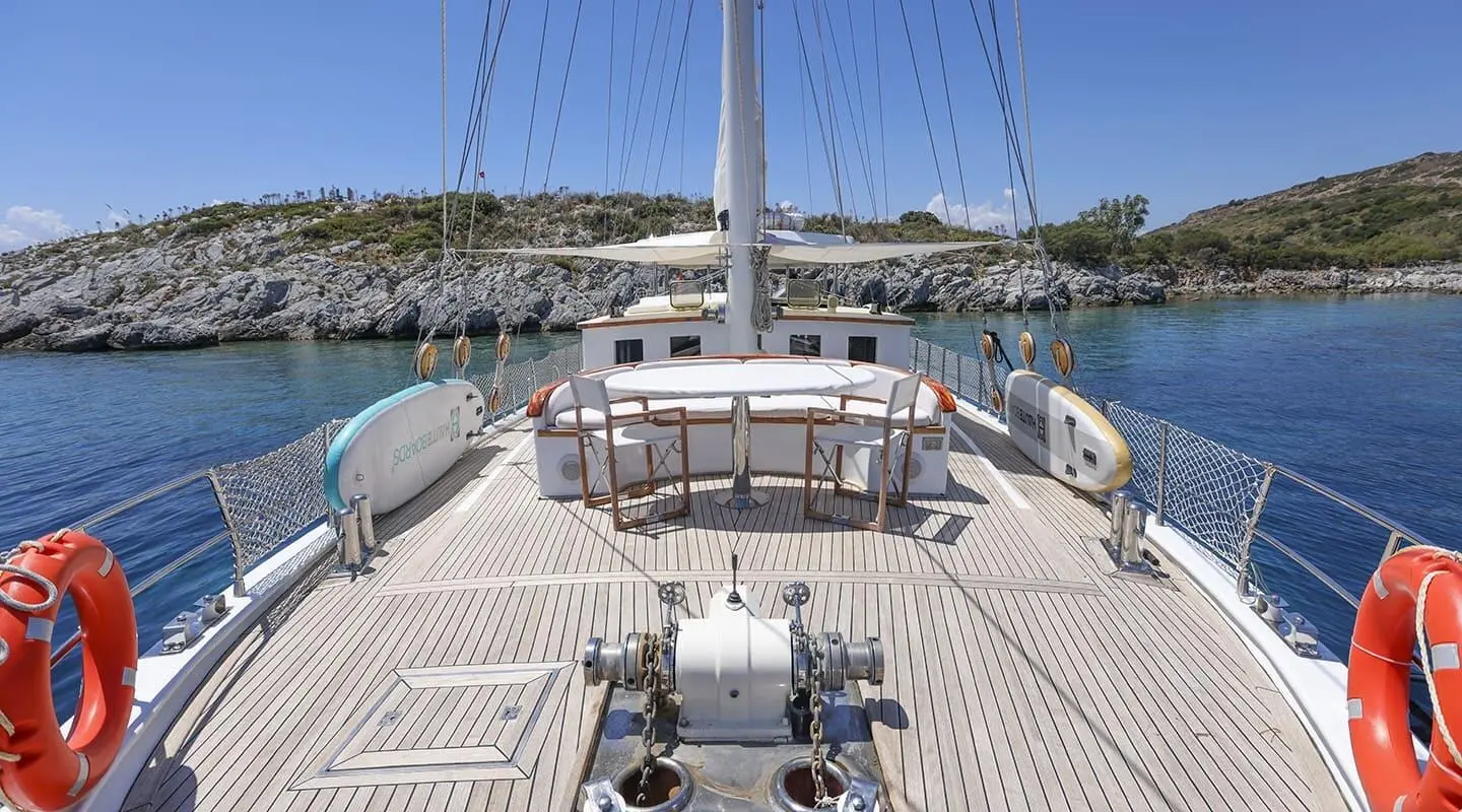 Gazella yacht deck view with ropes, railing, and calm blue sea at sunset
