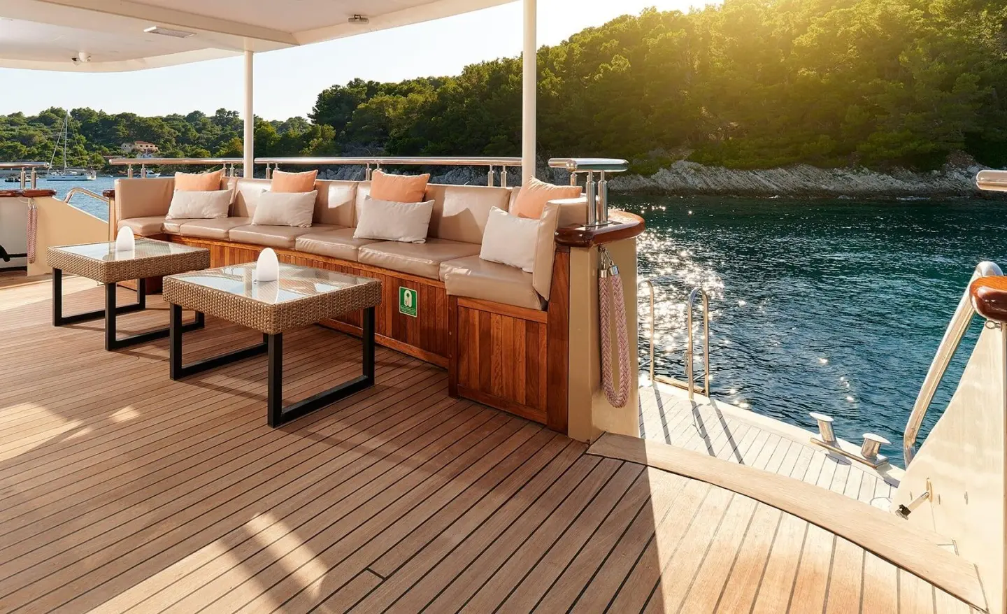 Queen Eleganza yacht deck at sunset with seating, wooden railing, and water views