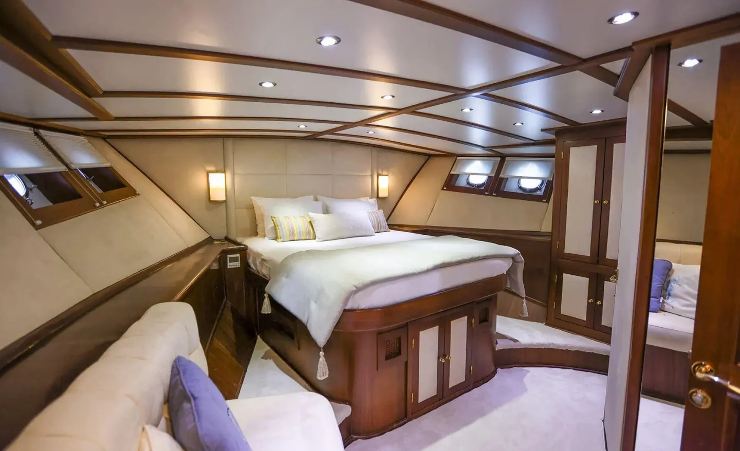 Gazella yacht interior with bed, wood cabinets, and seating under warm lights