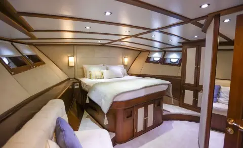 Gazella yacht interior with bed, wood cabinets, and seating under warm lights