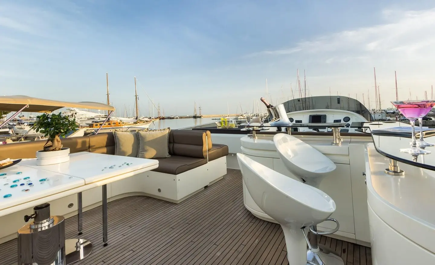 Amoraki motor yacht at a marina, flybridge view with deck seating and water nearby