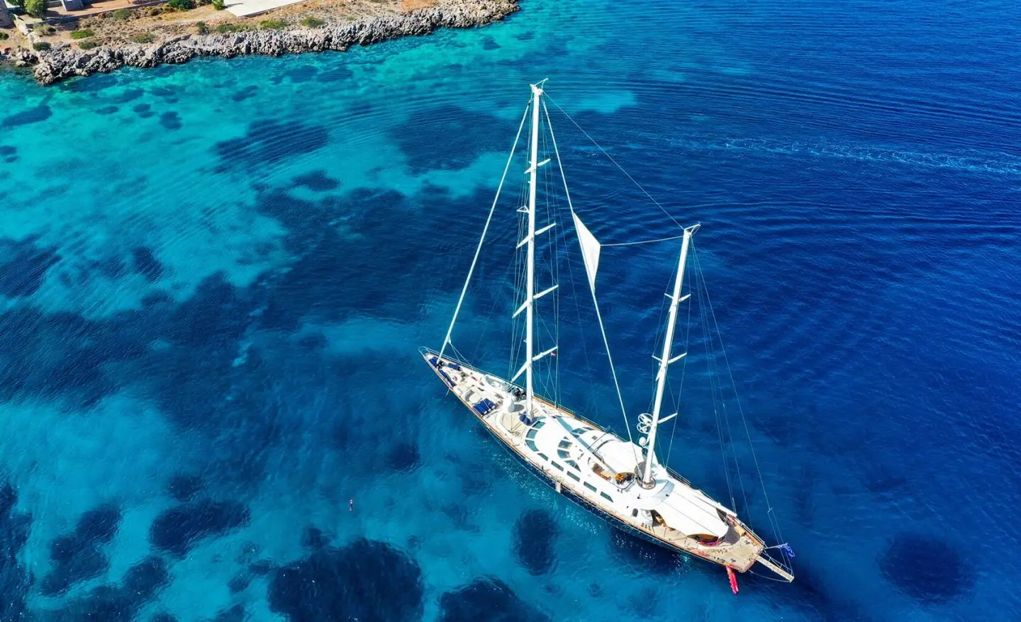 Sailing yacht Tamarita seen on clear blue water, aerial view near open sea