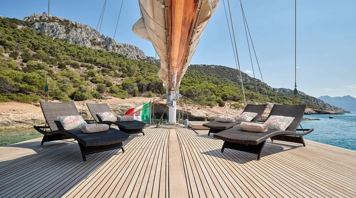 Deck view of a yacht named Myra with sun loungers on a teak deck at sunset
