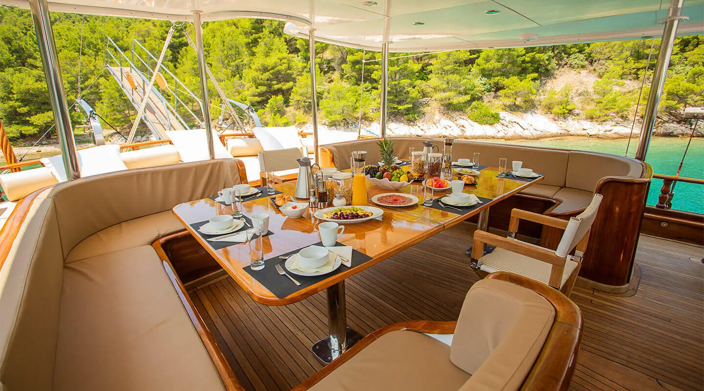 Dolce Vita yacht charter under a canopy with a dining table set for guests