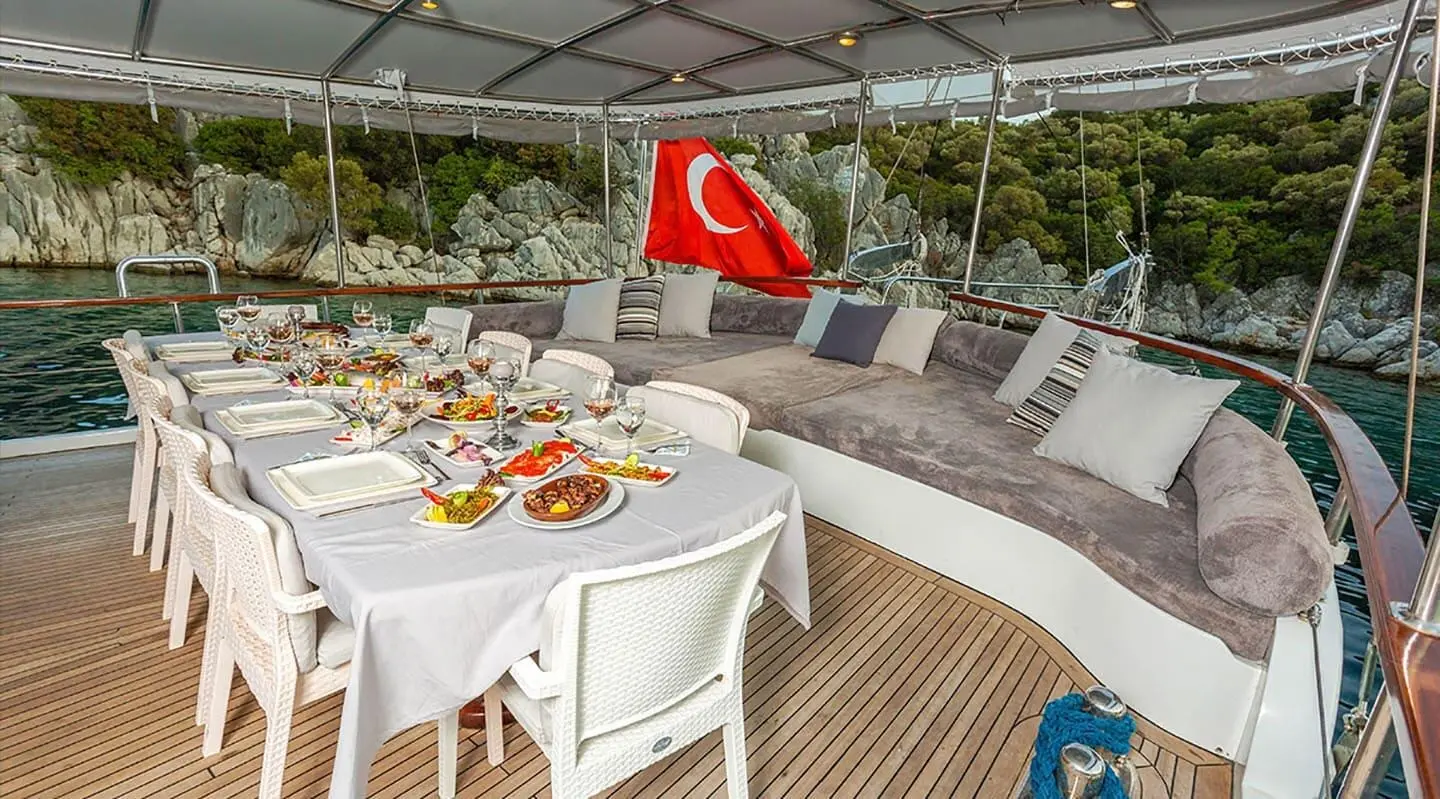 Sunset deck of a yacht with a round table set for dining and Turkish flag