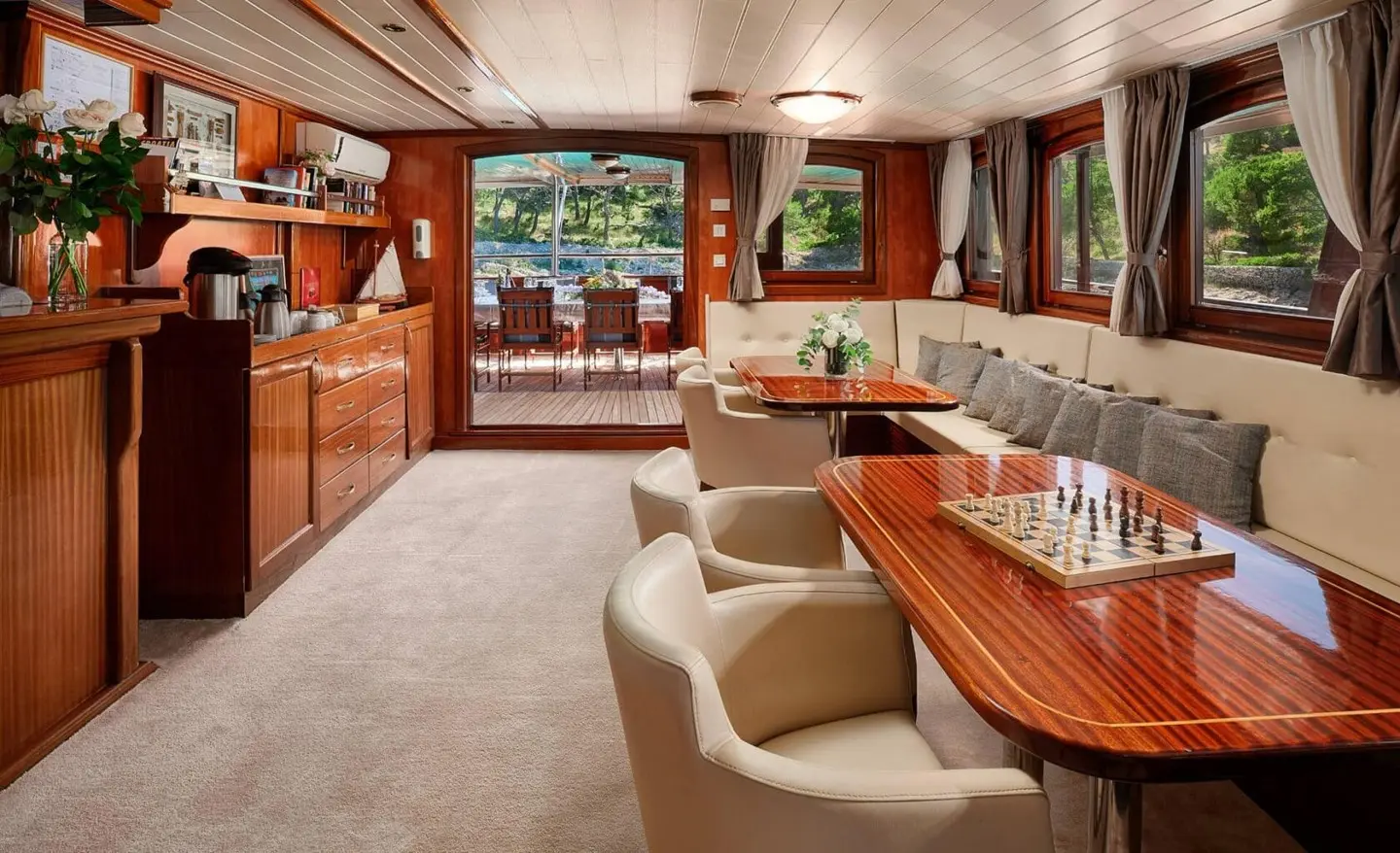 Luxurious yacht Luna salon interior with wooden paneling, cream leather seating, and a curved dining bar near windows
