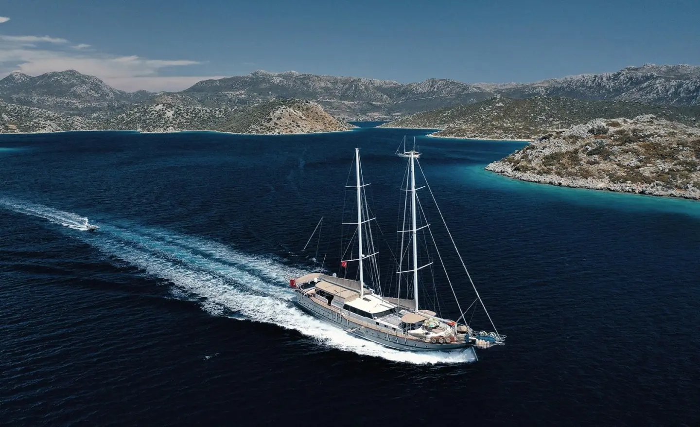 Nevra Queen luxury gulet sailing at sunset with coastal cliffs in background