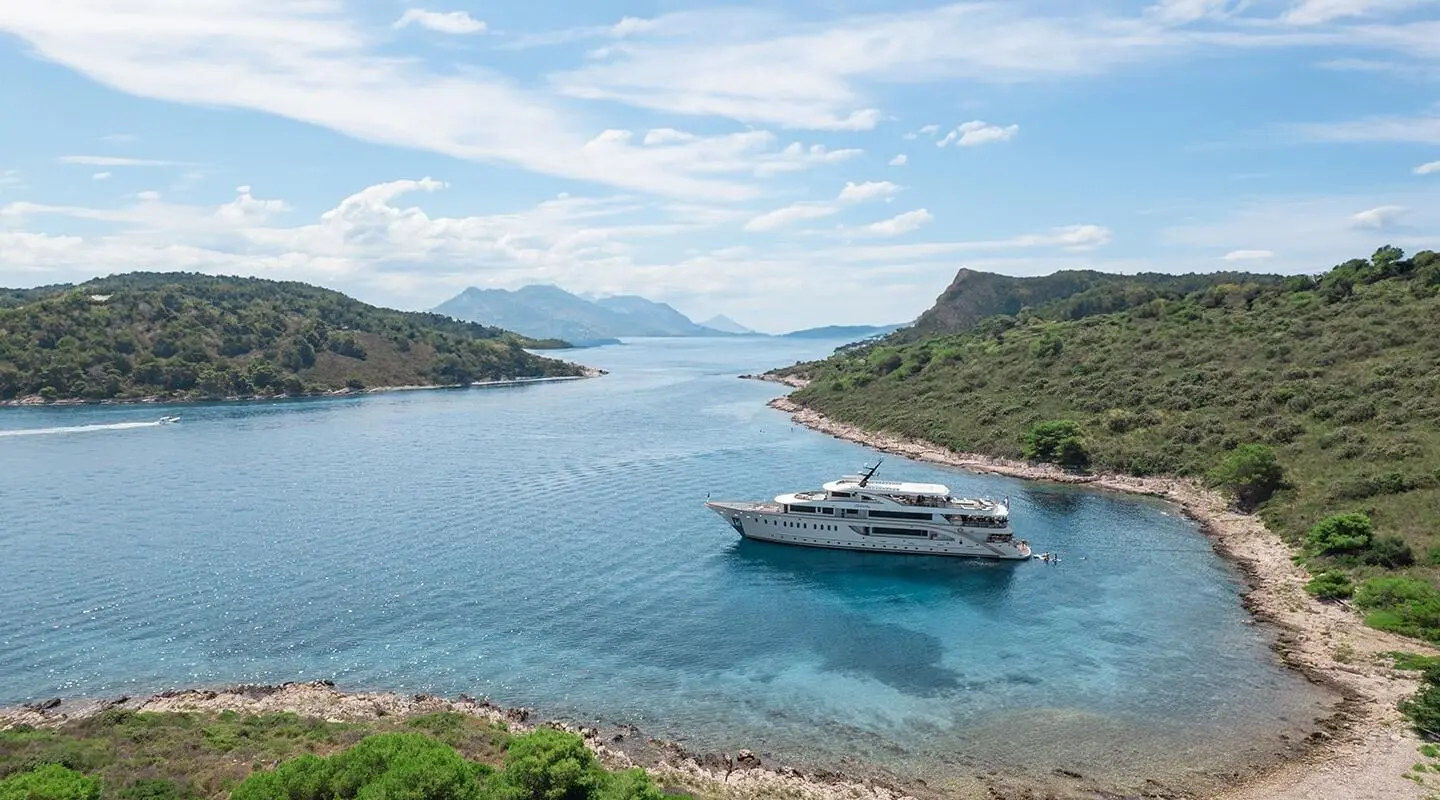Luxury Riva yacht anchored near a rocky coastline with clear blue water