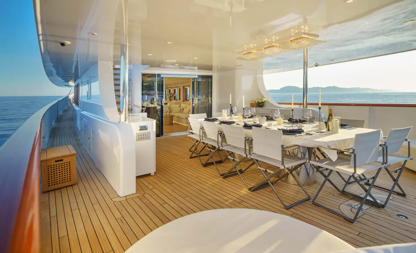 Maia yacht dining area with wooden deck, white seating, sun loungers, and ocean view