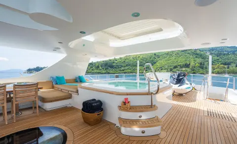 Modern yacht aft deck with jacuzzi, seating area and sun loungers