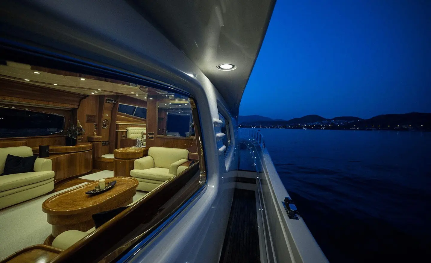Side view of Amoraki yacht at dusk, interior lights visible through windows
