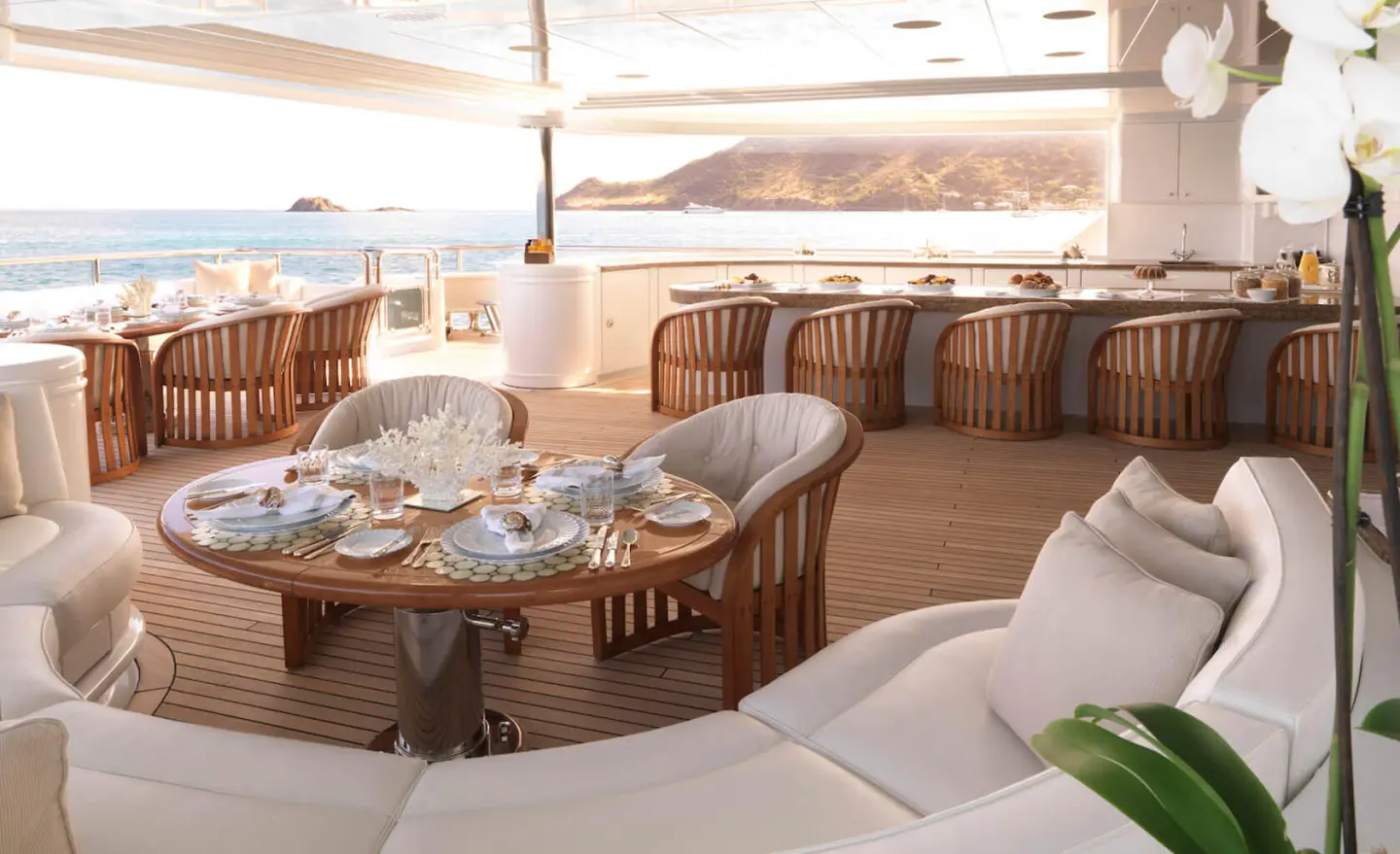 Apogee yacht deck dining area with wood table and cushioned seating under shade