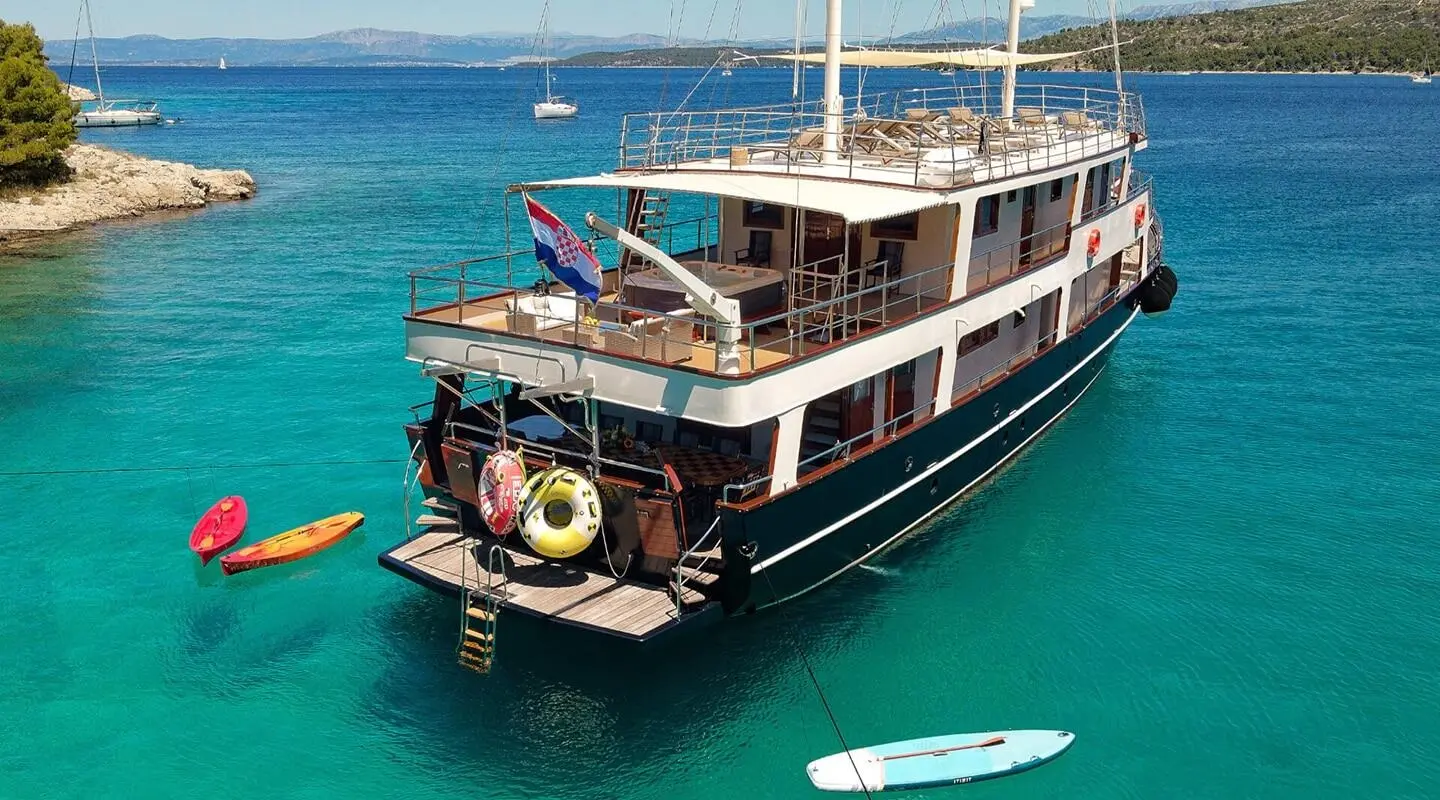 Luxury Luna yacht anchored in turquoise water, sunset glow on hulls