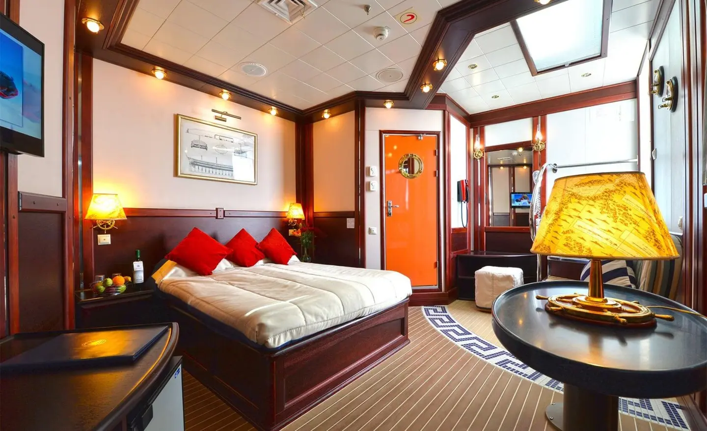 Interior of yacht Running on Waves with a bed, red pillows, and warm lighting