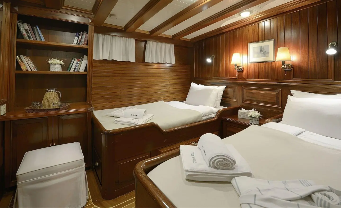 Cozy yacht cabin with two beds, wood-paneled walls, and a folded towel