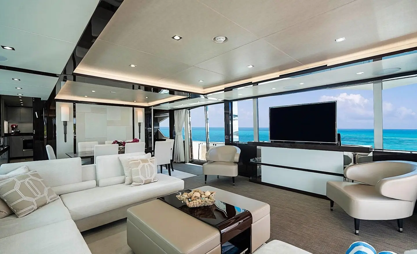 Luxurious yacht Quantum saloon with white seating, glass doors, and warm lighting