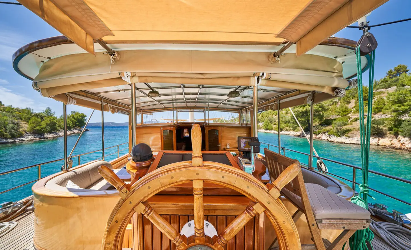 From the helm on Libra yacht, wooden wheel and ocean views at sunset